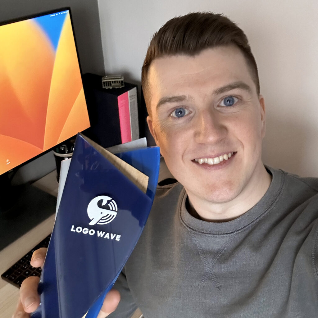 Liam Warsop is holding the trophy for winning first place at the Logo Wave Awards for his logo design for LEVEL, a health and wellbeing brand.