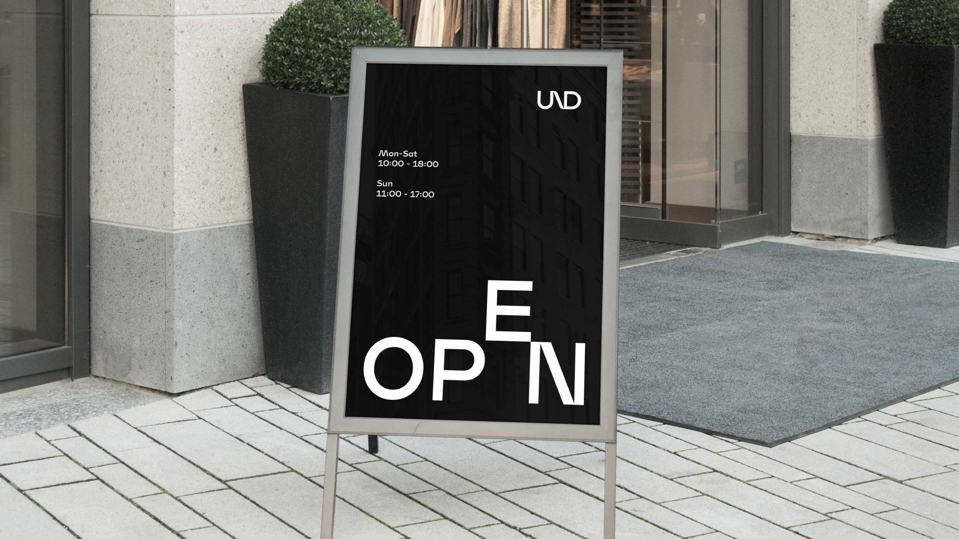 UND branded street signage displaying store opening times.